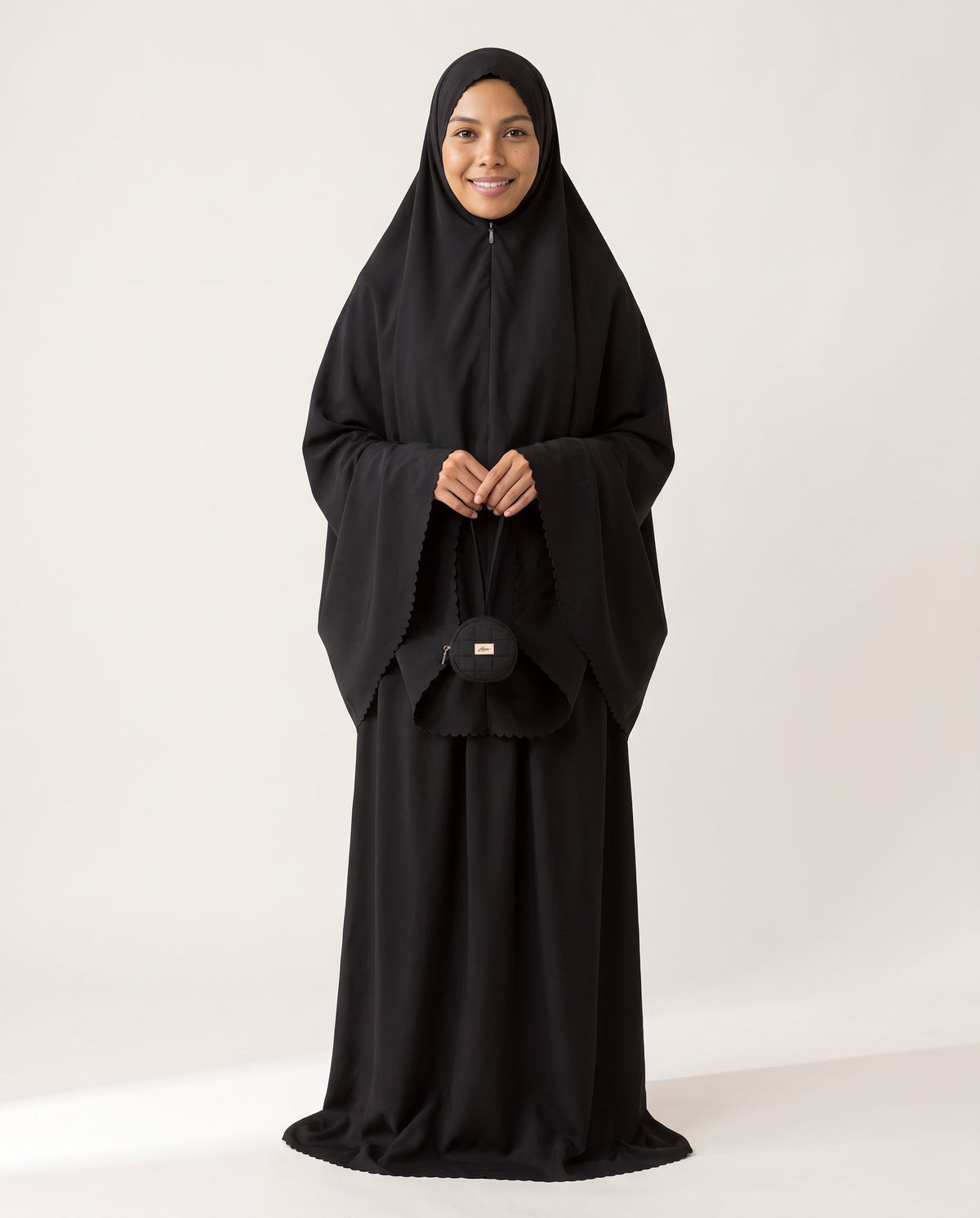 Pocket Mukena in Layl, black, holding the matching pouch
