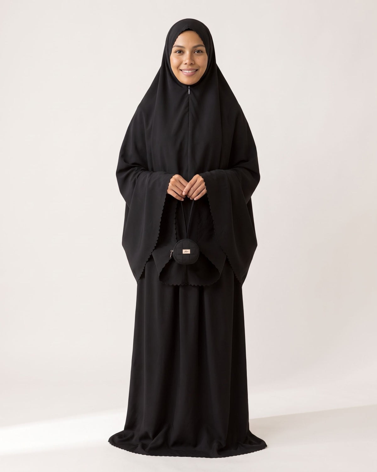 Pocket Prayer Outfit in Layl, black, holding the matching pouch