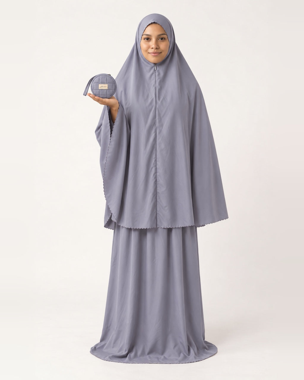 Pocket Prayer Outfit in Qamar, soft grey, presenting the pouch on her palm