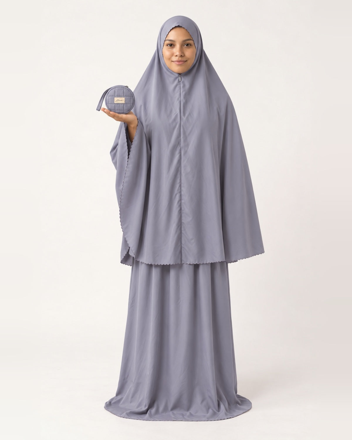 Pocket Prayer Outfit in Qamar, soft grey, presenting the pouch on her palm